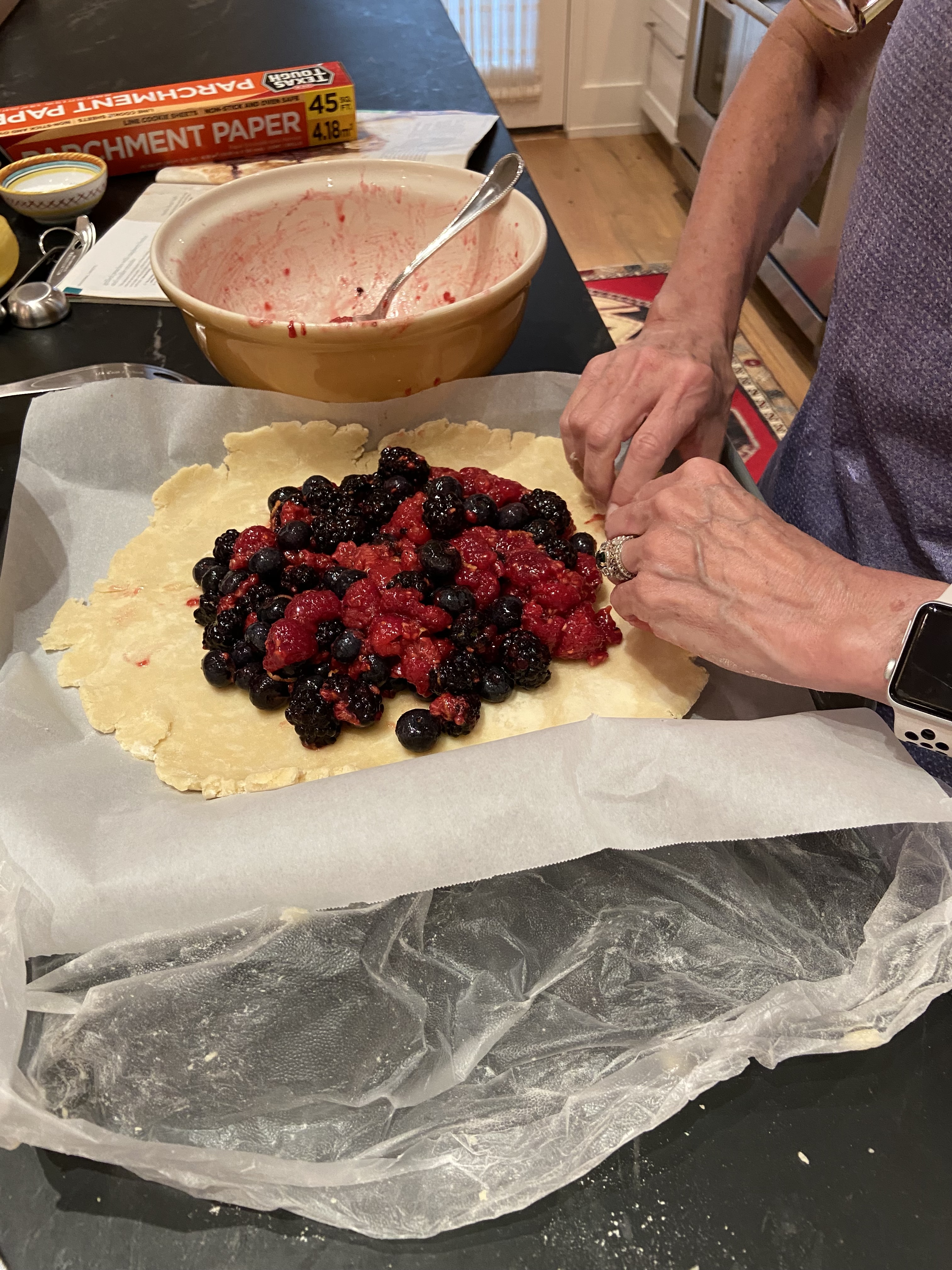 Hands folding pastry dough around fresh berries